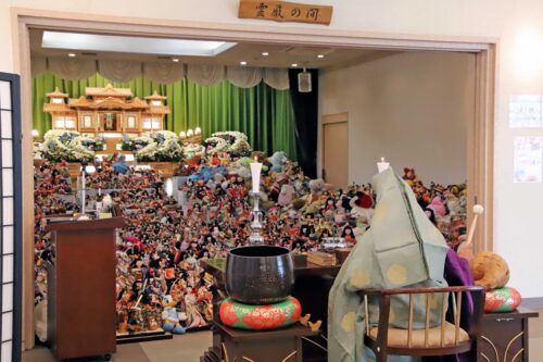 集まった人形などを前に読経する住職